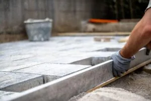 Contractor installing concrete patio base and leveling surface during residential construction project
